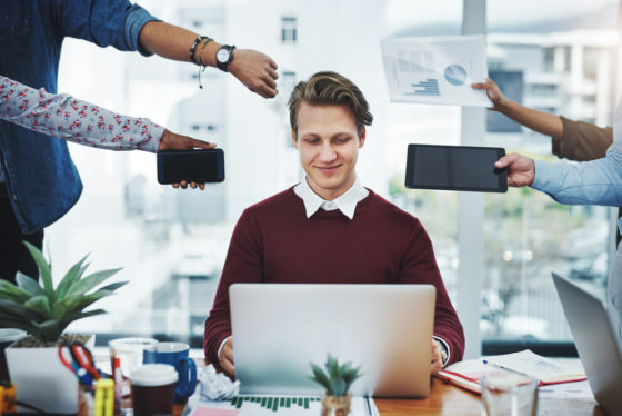 Shot of a young businessman using a laptop in a demanding office environment